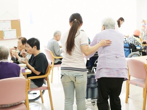 歩行のサポートを行っているスタッフと食事を楽しんでいる入居者様