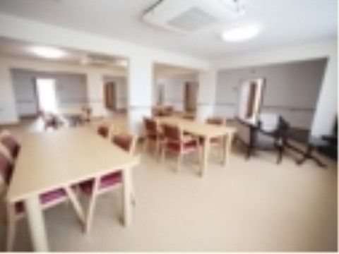 壁と床が白い明るい部屋に、座面と背もたれが濃いピンク色の椅子が４脚、白木のテーブルが1台置かれている。