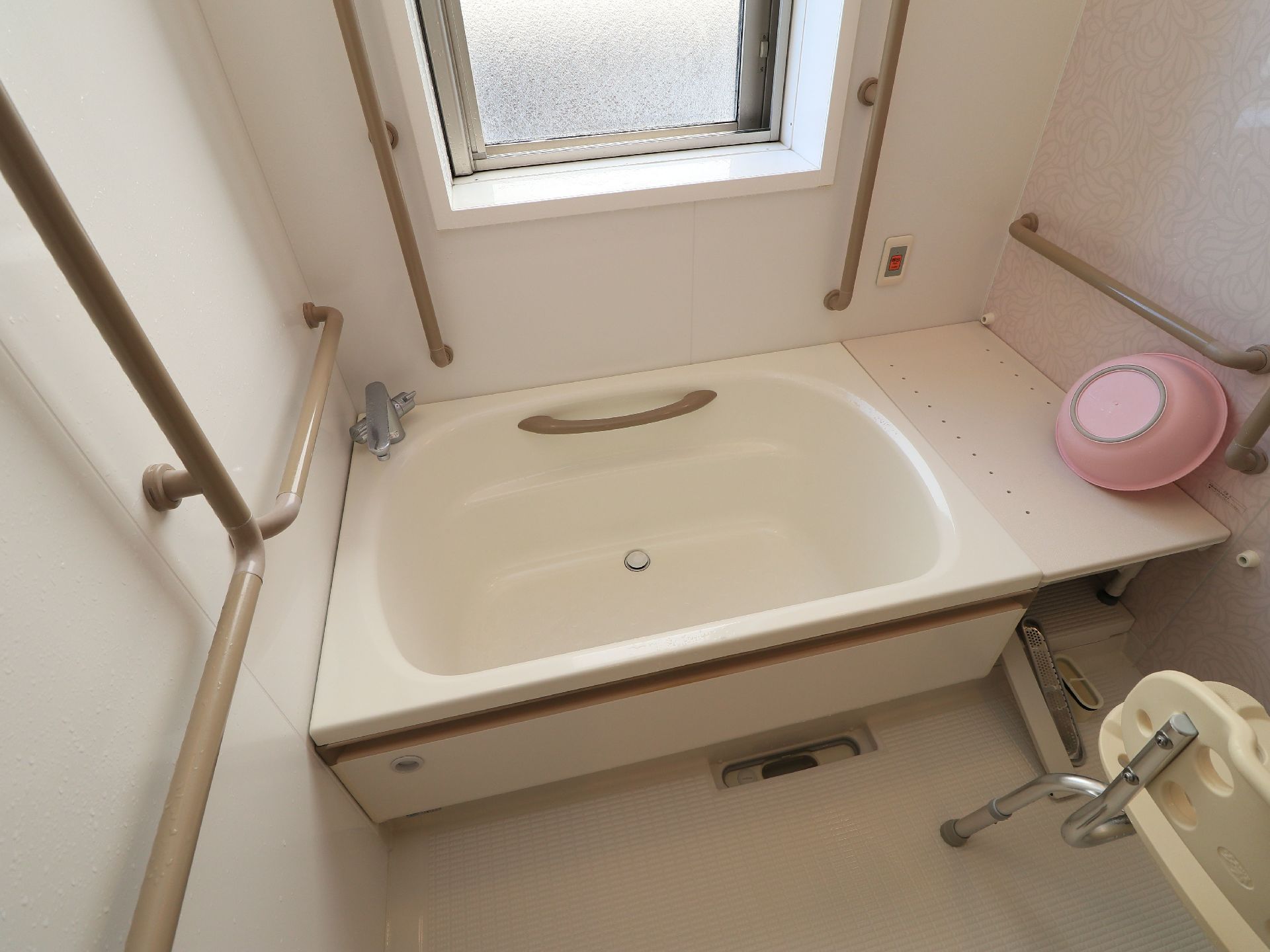 白を基調とした、シンプルな浴室である。縦窓が備えつけられている。随所には、ダーク系の手すりが設置されている。