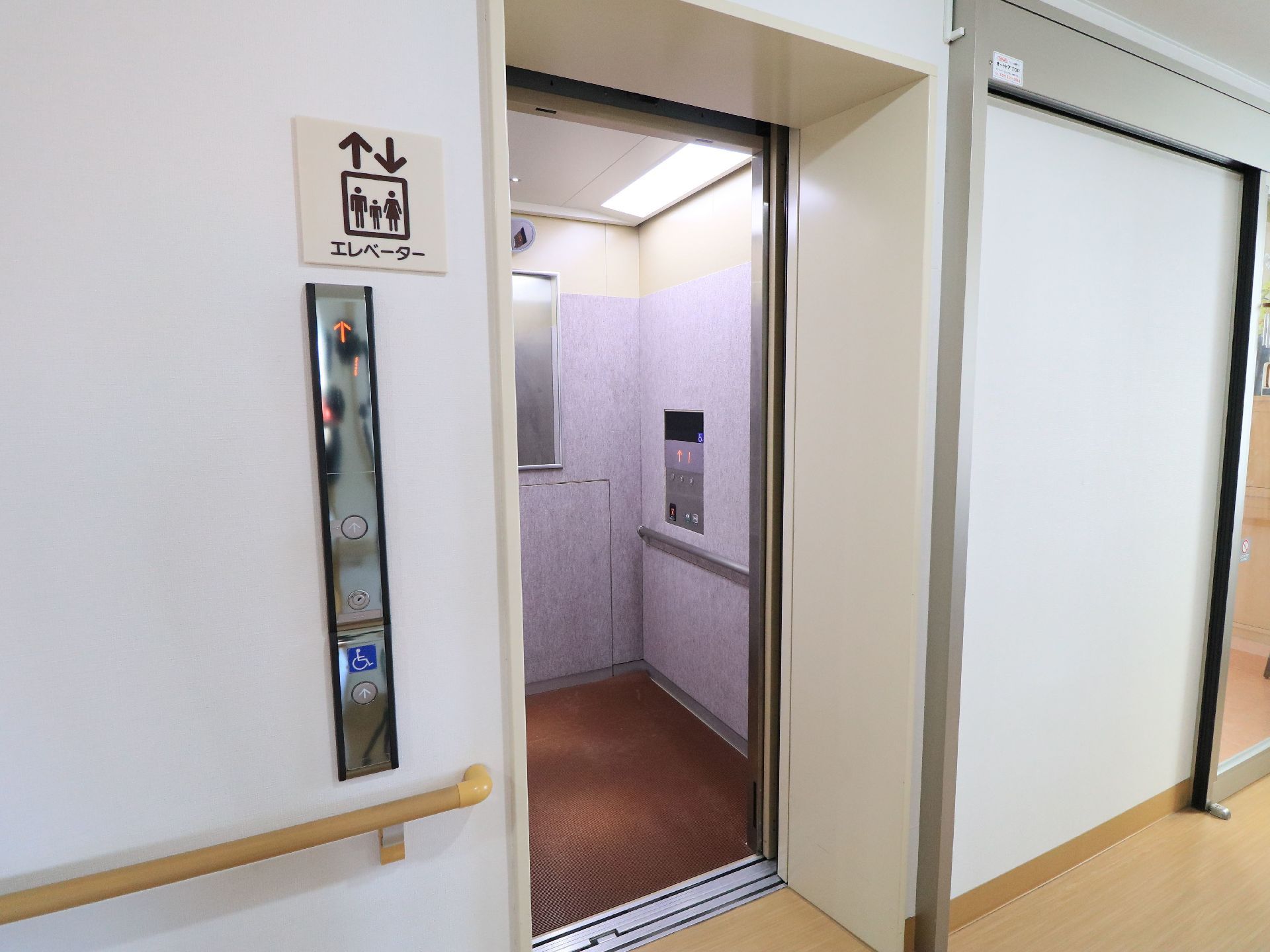エレベーター前の壁には廊下側から続く手すりを設置している。内部には鏡を取りつけ、天井の大型照明で十分な明るさを確保している。