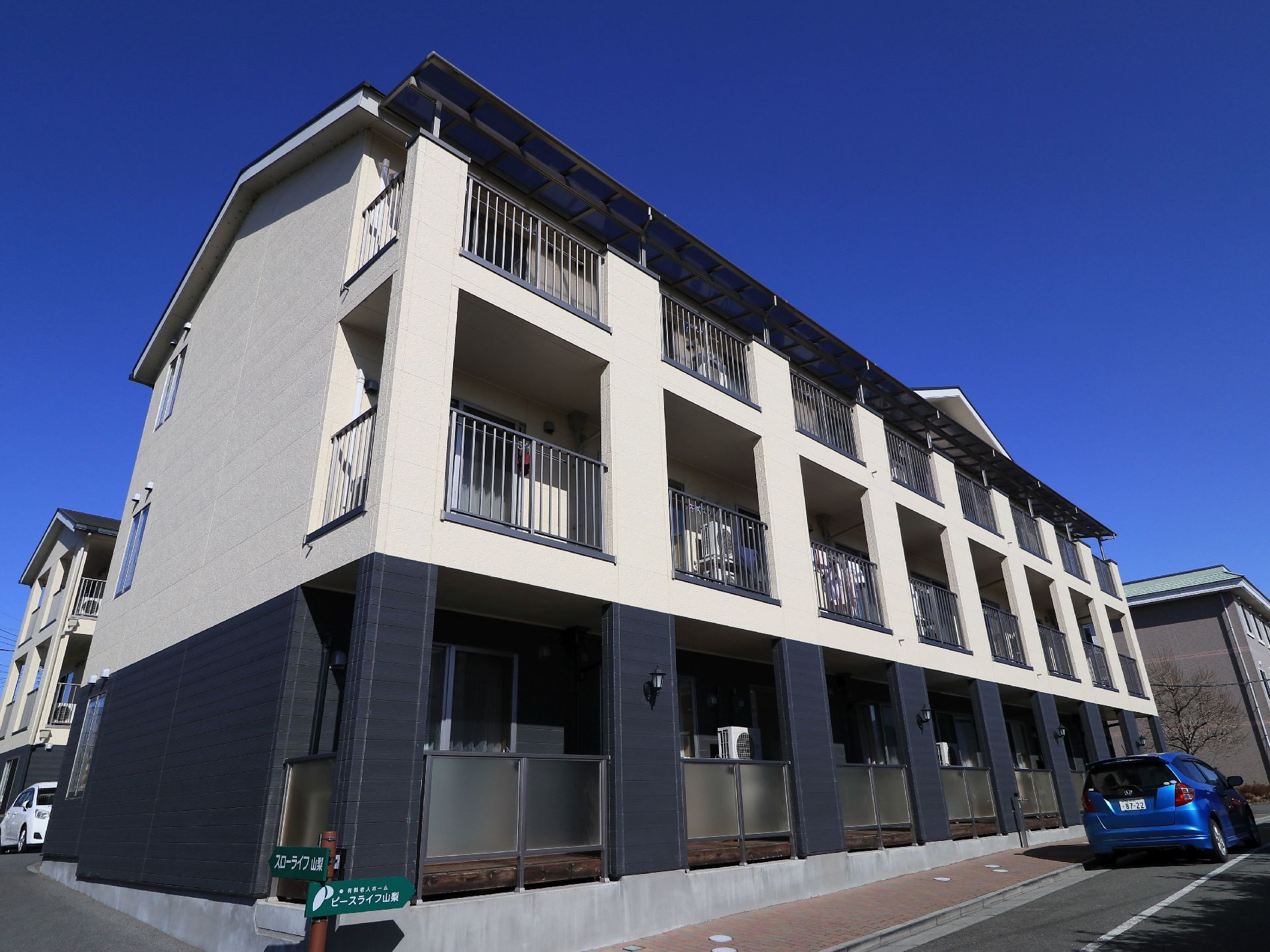 施設の建物は三階建てで、一階部分を黒、上階を白で色分けしている。窓の外にはベランダを設け、採光性の良いフェンスを設置している。