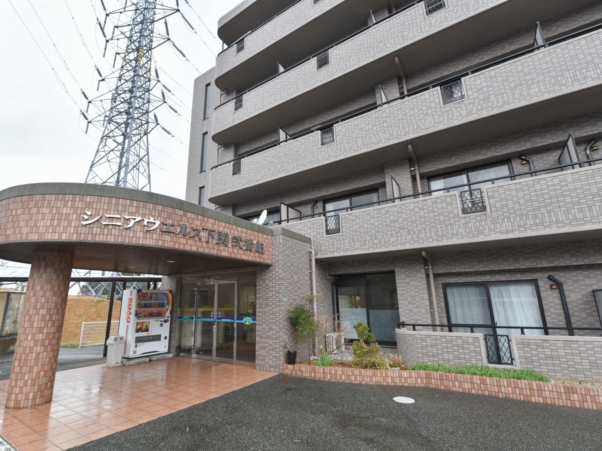 レンガ調の外壁が落ち着いた雰囲気の施設の外観。玄関前のアプローチには屋根が設置されている。敷地から玄関までバリアフリーになっている。