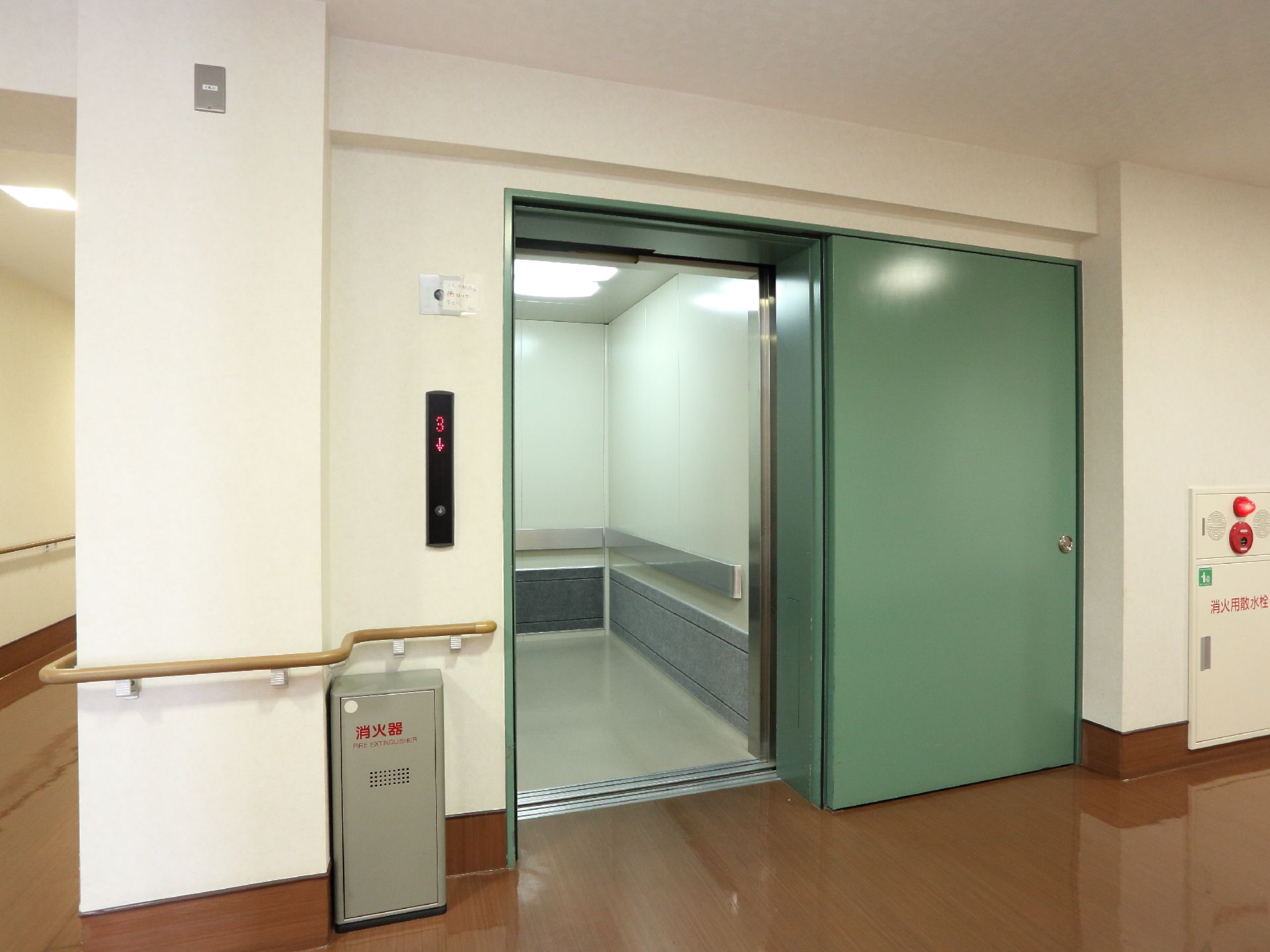 ストレッチャーに横になったまま乗れる大型エレベーターが設置されています。周囲に消火器・消火栓を備え、万全の防災対策をしています。