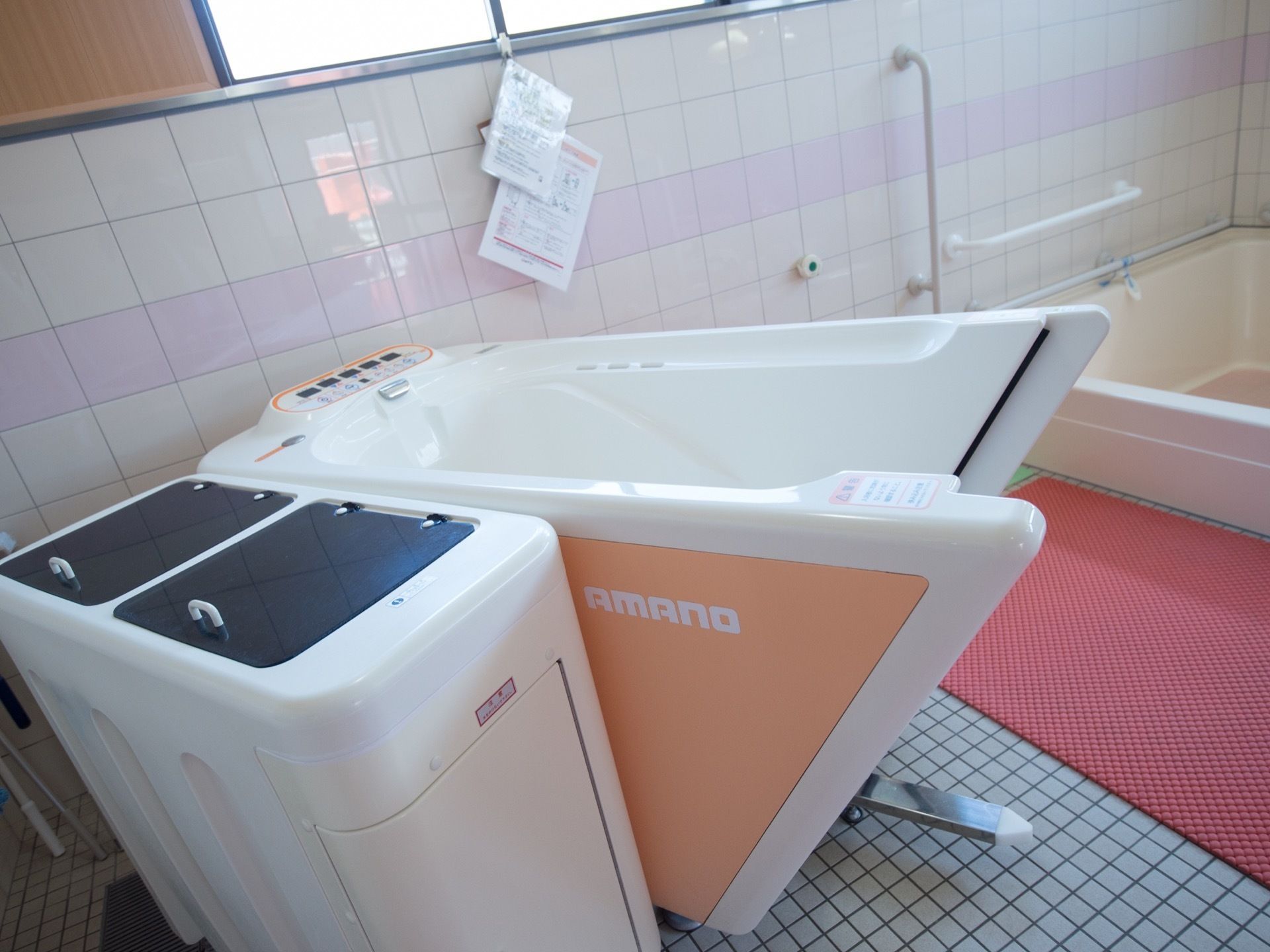 介護浴槽が用意されている。壁はタイル張りになっており、手すりが備えつけられている。床には滑り止めマットが敷かれている。