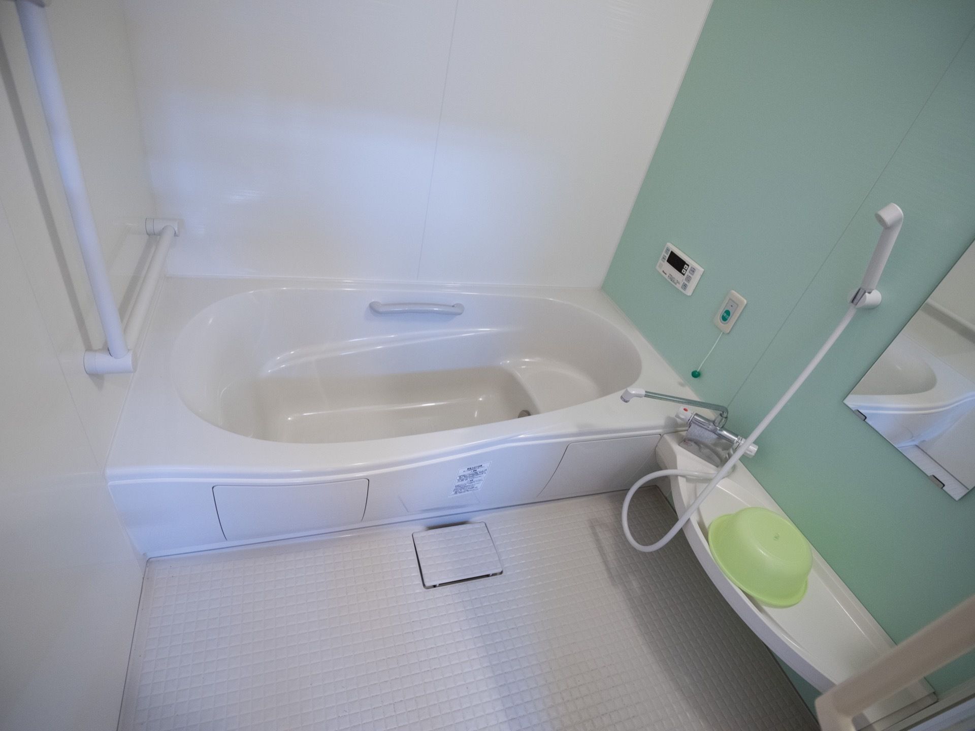 白を基調とした内装の浴室は、一部の壁をアクセントでパステルグリーンになっている。明るくおしゃれな雰囲気の空間。