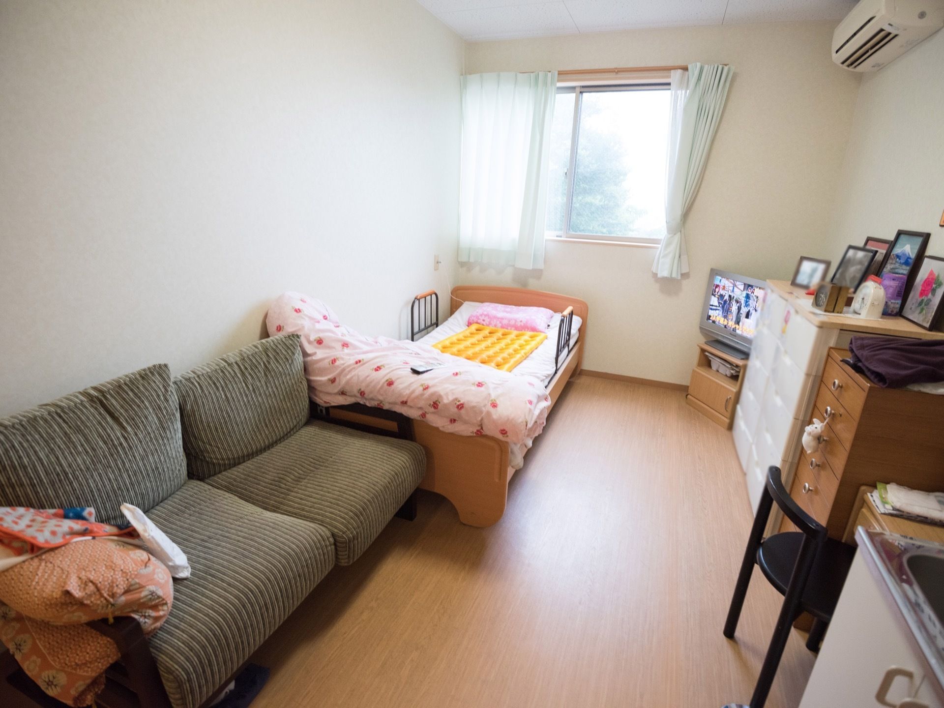 明るく清潔感のある居室は、ワンルームタイプの間取りになっている。室内にはキッチンなどの設備が置かれている。