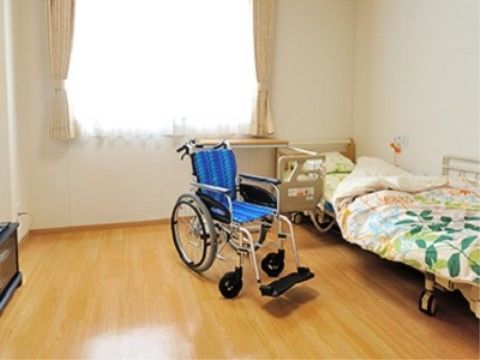 バリアフリーとなっている居室は、車椅子で過ごしやすい広さがある。窓辺にあるベッドには緊急通報装置が設置されており、安全に配慮されている。
