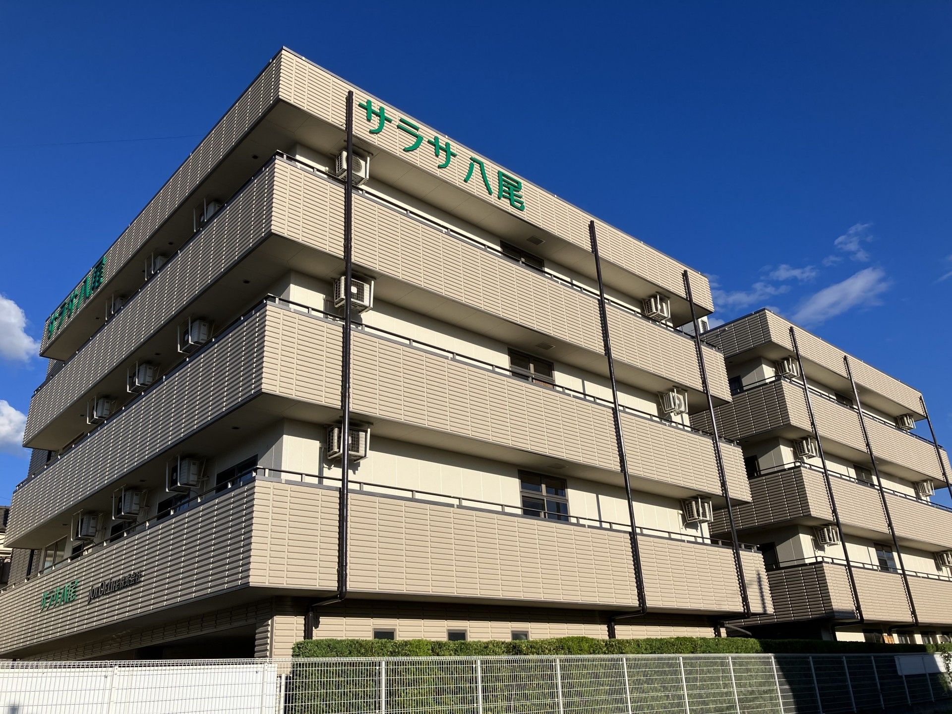木々が植えられた、緑豊かな環境に建つ施設の外観と看板