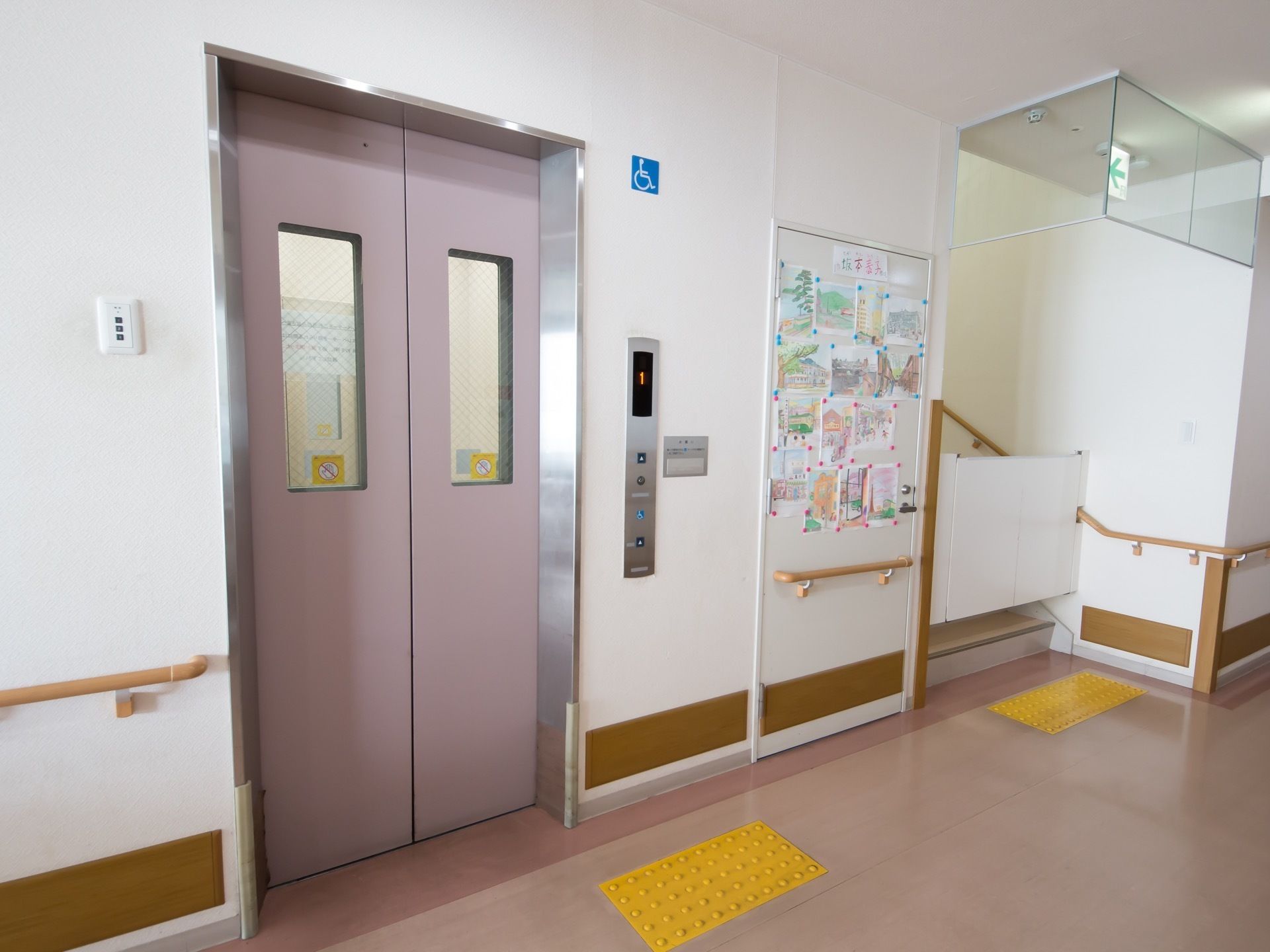 廊下の階段脇にはエレベーターが設置されており、車椅子でも利用可能である。床には点字ブロックが設置されている。