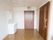 白壁と床がフローリング材の居室である。部屋の中に、収納棚と鏡がついた洗面台が設置されている。入口の扉には明り取りのスリットが入っている。