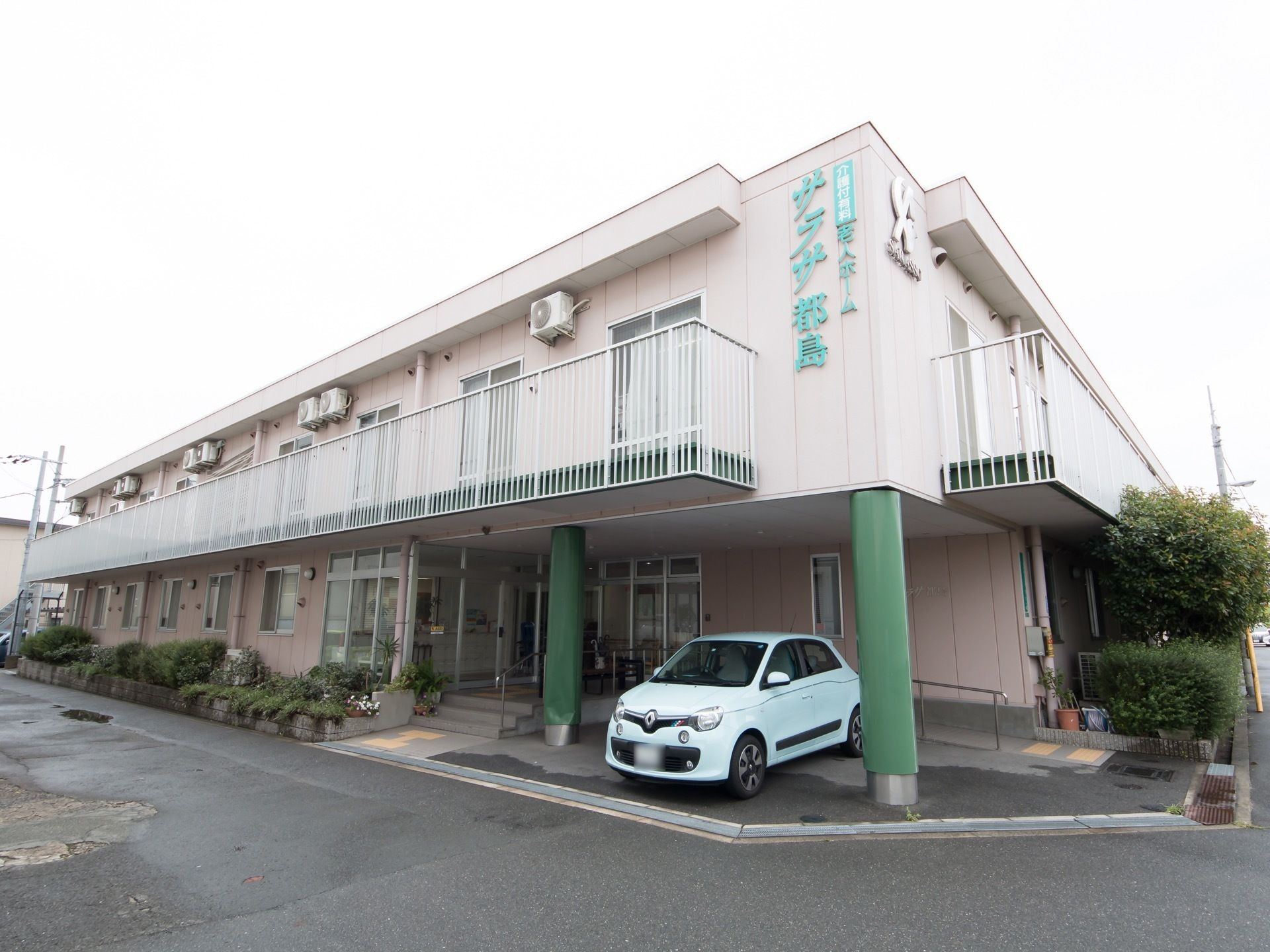 ２階建ての施設の建物は閑静な住宅街に建っている。玄関前には手すり付きの階段とスロープが設けられている。