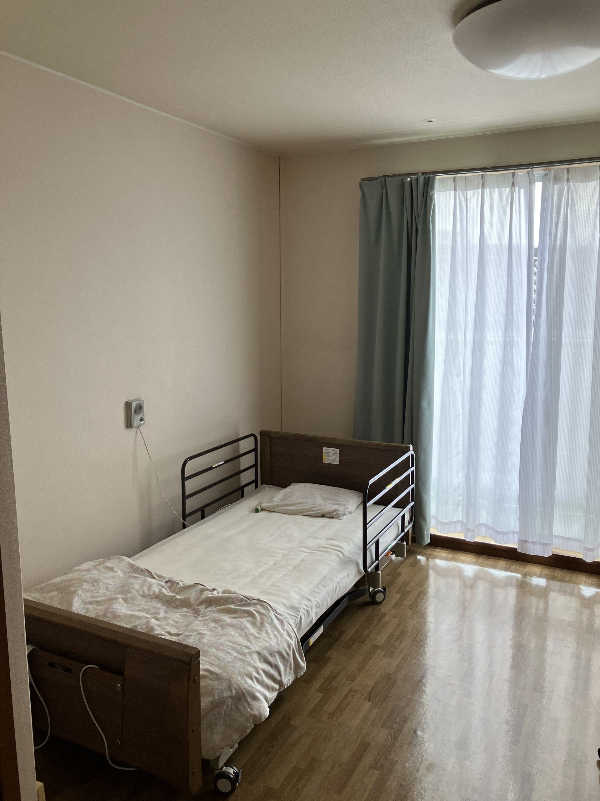 居室には介護ベッドが備わっており、両側に転落防止柵がついているので安心である。掃き出し窓から入る陽光で、朝は快適に目覚めていただける。