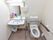 洋式トイレの横には洗面台が設置されている。洗面台正面の壁には鏡や照明、小さな棚や手拭き用のペーパーが取り付けられている。