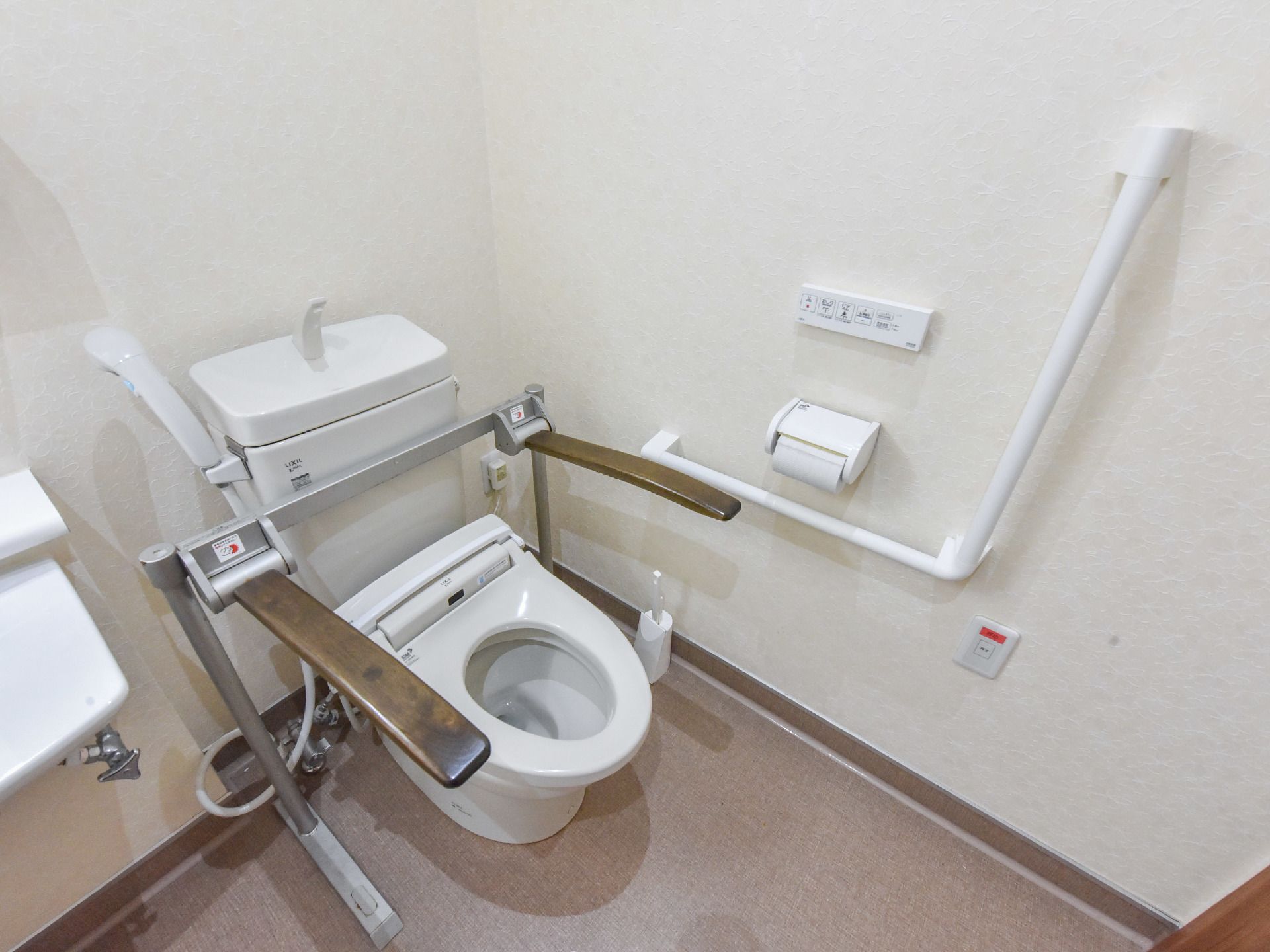 トイレには洋式トイレが設置され、シャワーや左右にひじ掛けた追加されている。隣の壁には手すりが取り付けられている。