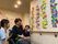 館内に飾られたあさがおの掲示物を眺めて談笑するスタッフと入居者