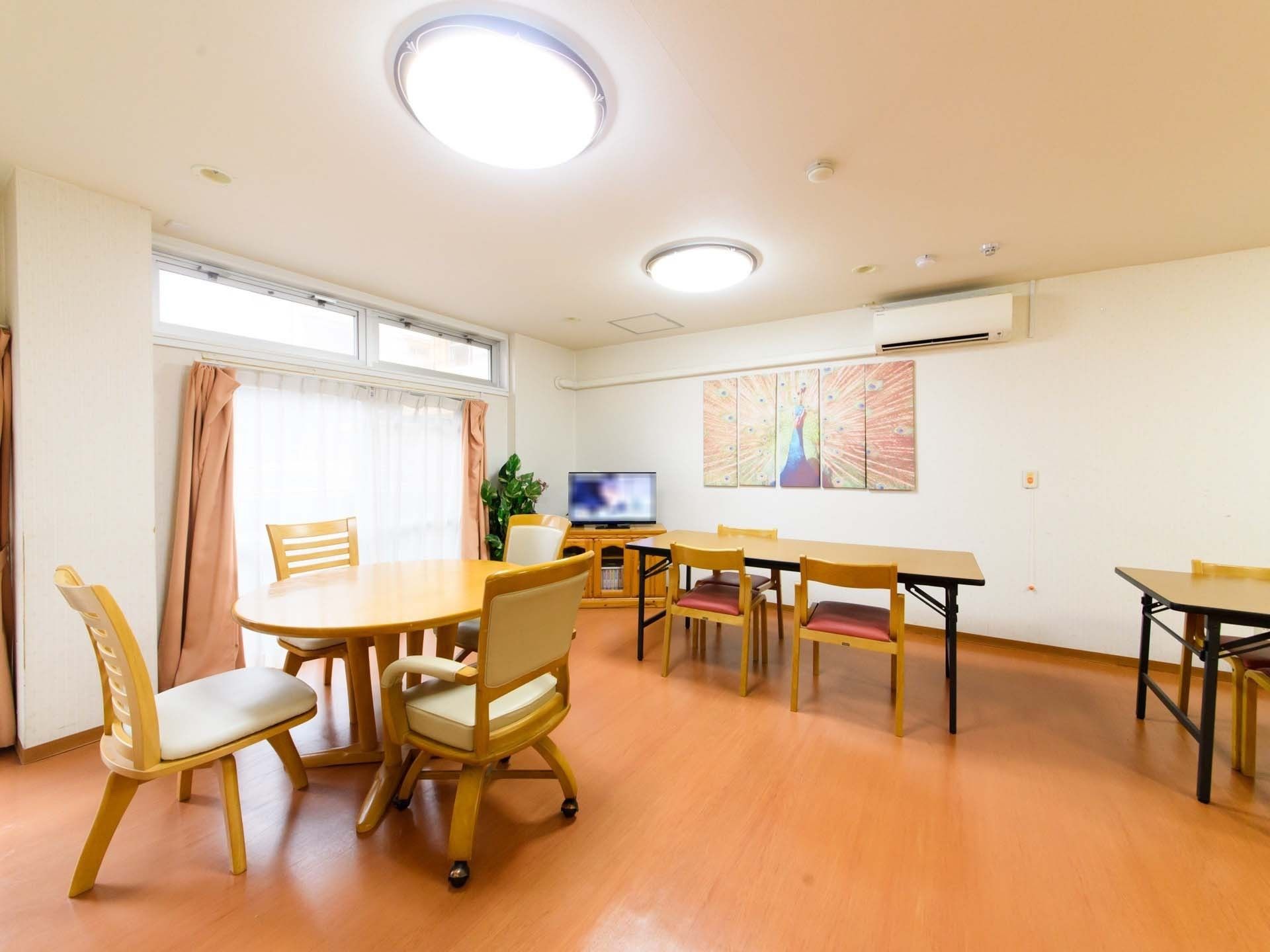 明るい多目的室にはテーブル、椅子が入居者様の移動空間を確保しつつ配置されているため、衝突などのリスクを回避できる。