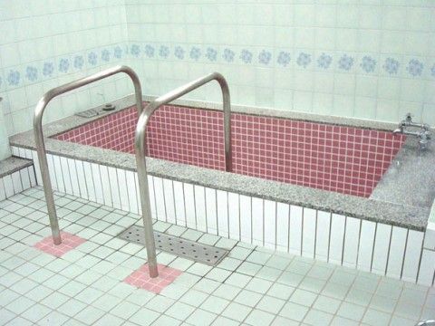 タイル張りの清潔な浴室である。安全に湯船への出入りをしていただけるよう、浴槽には２本の手すりが設置されている。