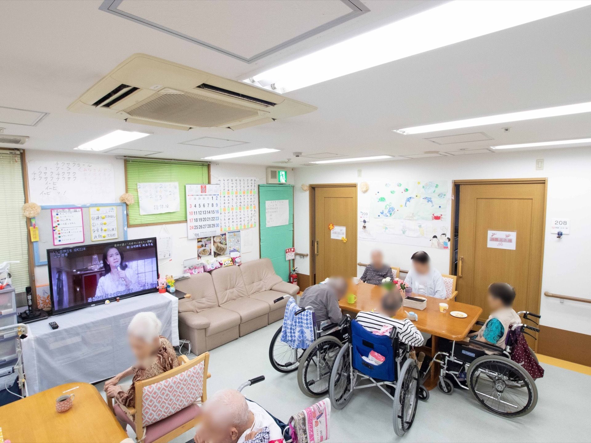 テレビが設置された開放的なリビング。お茶を飲んだり、歓談したり、入居者様が思い思いの時間を過ごしている。