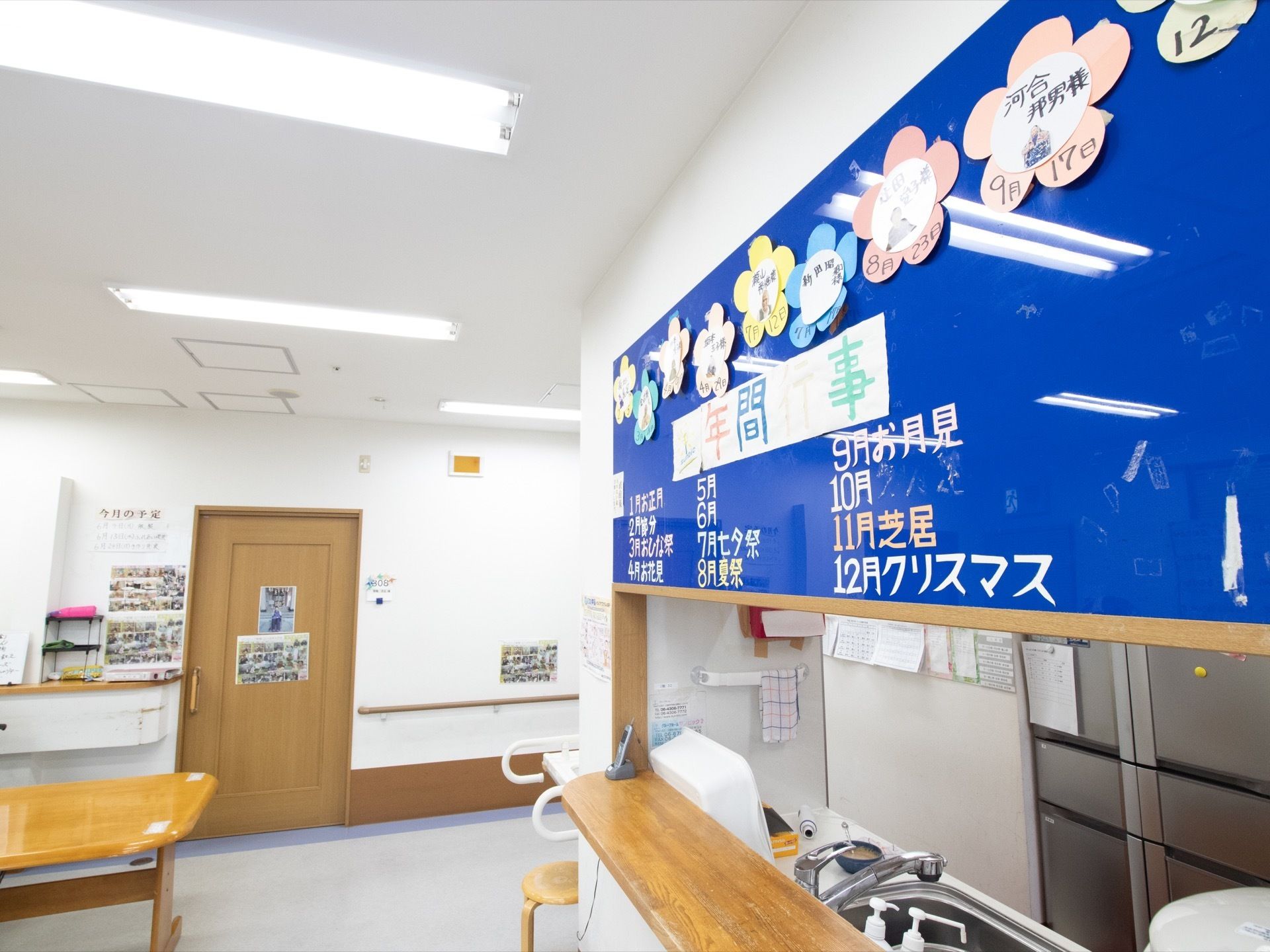 広々としたカウンターキッチン上には、年間行事や入居者様の誕生日が書かれた青いボードが設置されている。