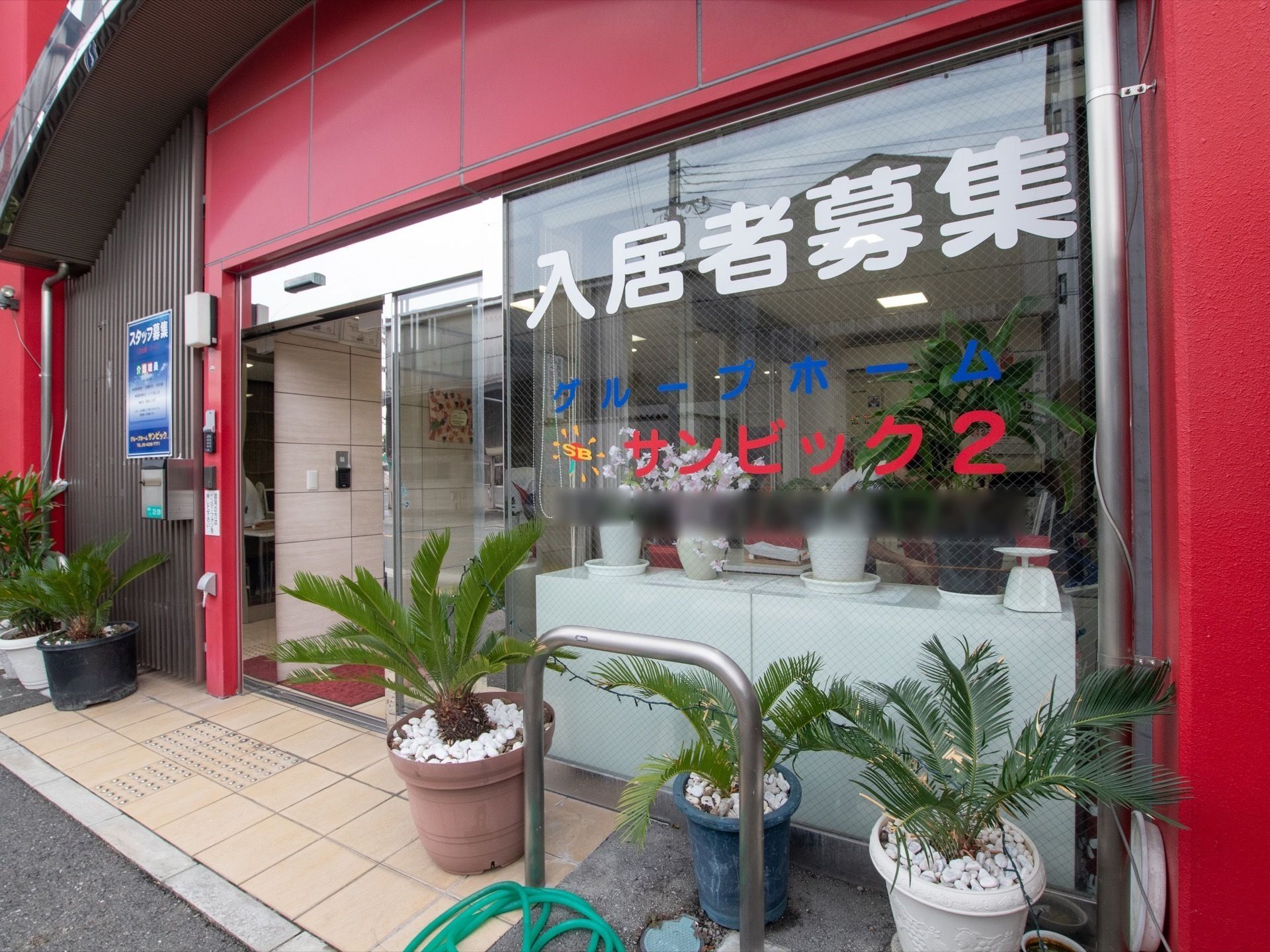 施設名称が赤色の大きな文字でガラス窓に書かれている玄関脇