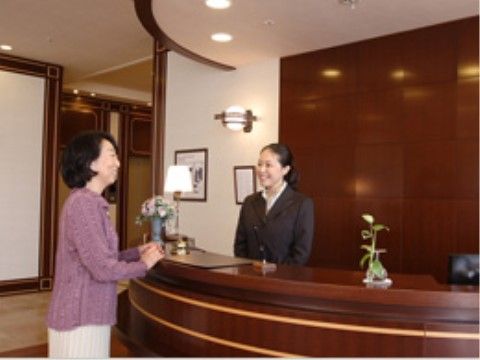 ホテルのような受付カウンターで、コンシェルジュと話す入居者の女性