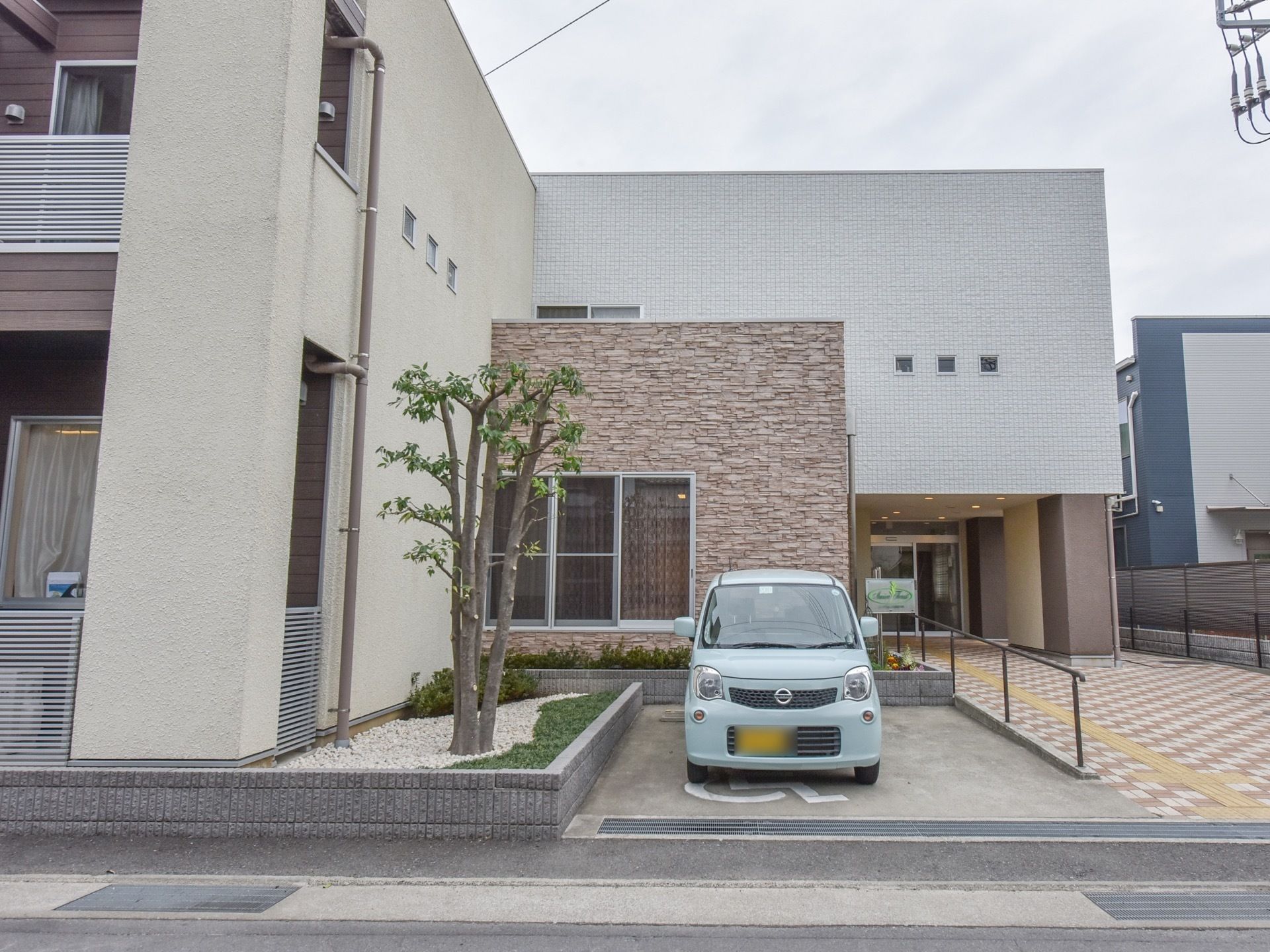 玄関正面からの写真。玄関までは段差がなくスロープになっていて通路の幅が広い。駐車スペースが１台分ある。