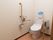 トイレは、壁のボタンを押すことによって水を流すことができるので使いやすい。白い壁で清潔感のある空間になっている。