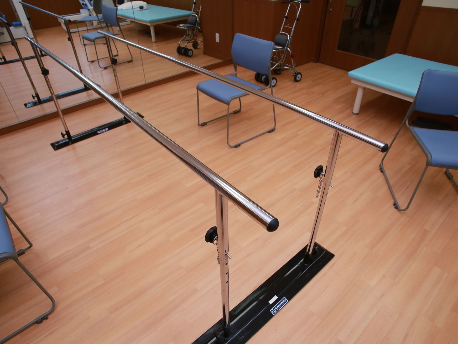 鏡張りの壁の前に、歩行訓練用の器具が置かれており、その周囲には、椅子やベンチ、手押し車などが用意されている。