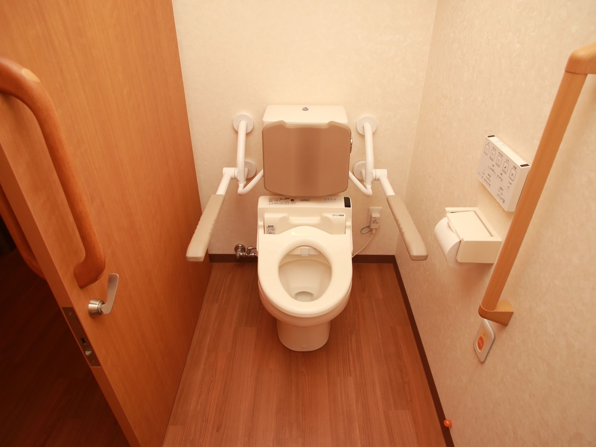 トイレの出入口の扉は引き戸になっている。壁の手すりの下には、非常時用の呼び出しブザーが設置されている。
