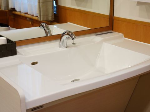 施設内にある、洗面台。鏡が付いていて、蛇口はオートマティックタイプである。カゴに紙コップが入っている。