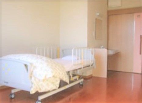 綺麗にワックス掛けされているフローリングにベッドが1つ置かれている居室
