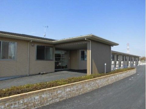 エントランスまでゆるやかなスロープがついている、広い敷地に建つ平屋の建物