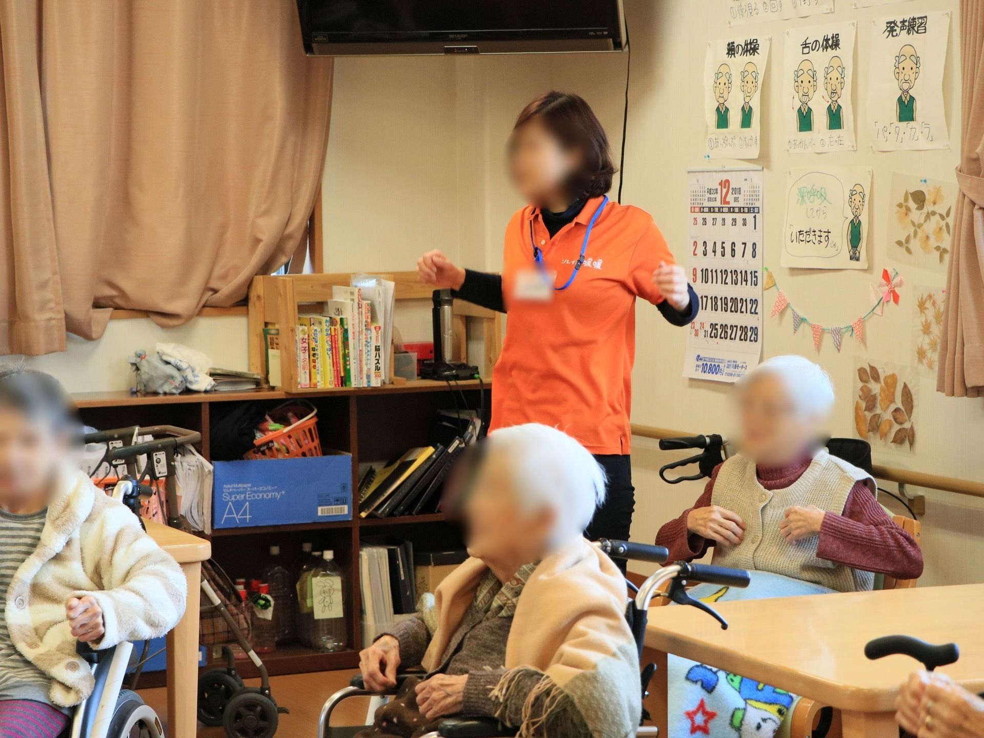 壁に沿って棚が用意されており、ペットボトルやファイルなどさまざまな物が置いてある。棚の上にはラックがあり、本が収納されている。