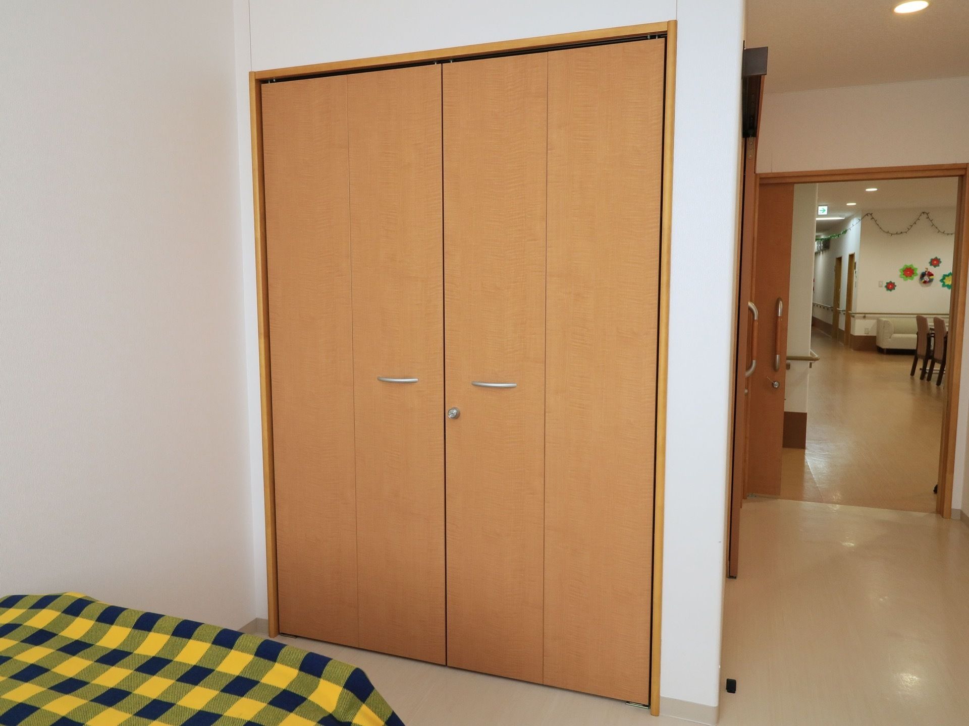 食堂のすぐそばに居室がある。居室の入口は引き戸になっている。室内には、折り戸タイプの背の高い収納スペースがある。