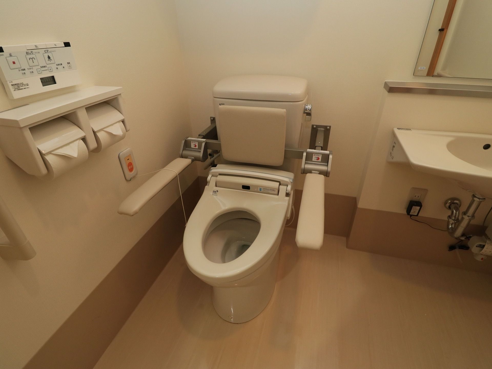トイレは暖房洗浄機能つき便座になっている。背もたれや可動式のひじ掛け、ナースコールボタンがついている。