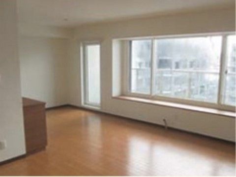 大きな窓から外の風景が見えているフローリングの床の広い部屋