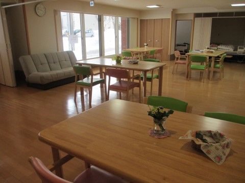 フローリングの部屋に複数のテーブルセットを配置している。壁には大きな窓を設け、その脇にソファーを置いている。