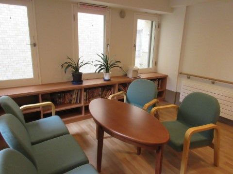 フローリングの部屋に椅子とテーブルを置いている。窓際には収納棚を設置し、たくさんの本を用意している。