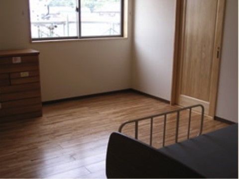 ベッドと収納があり、ドアと床が木調の落ち着きのある部屋