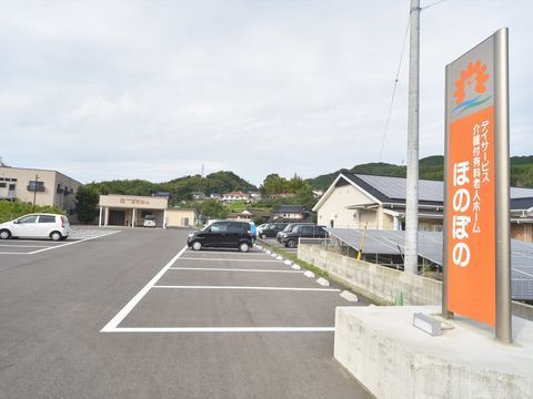 施設の看板があり、数台の車が止まっている広々とした駐車場