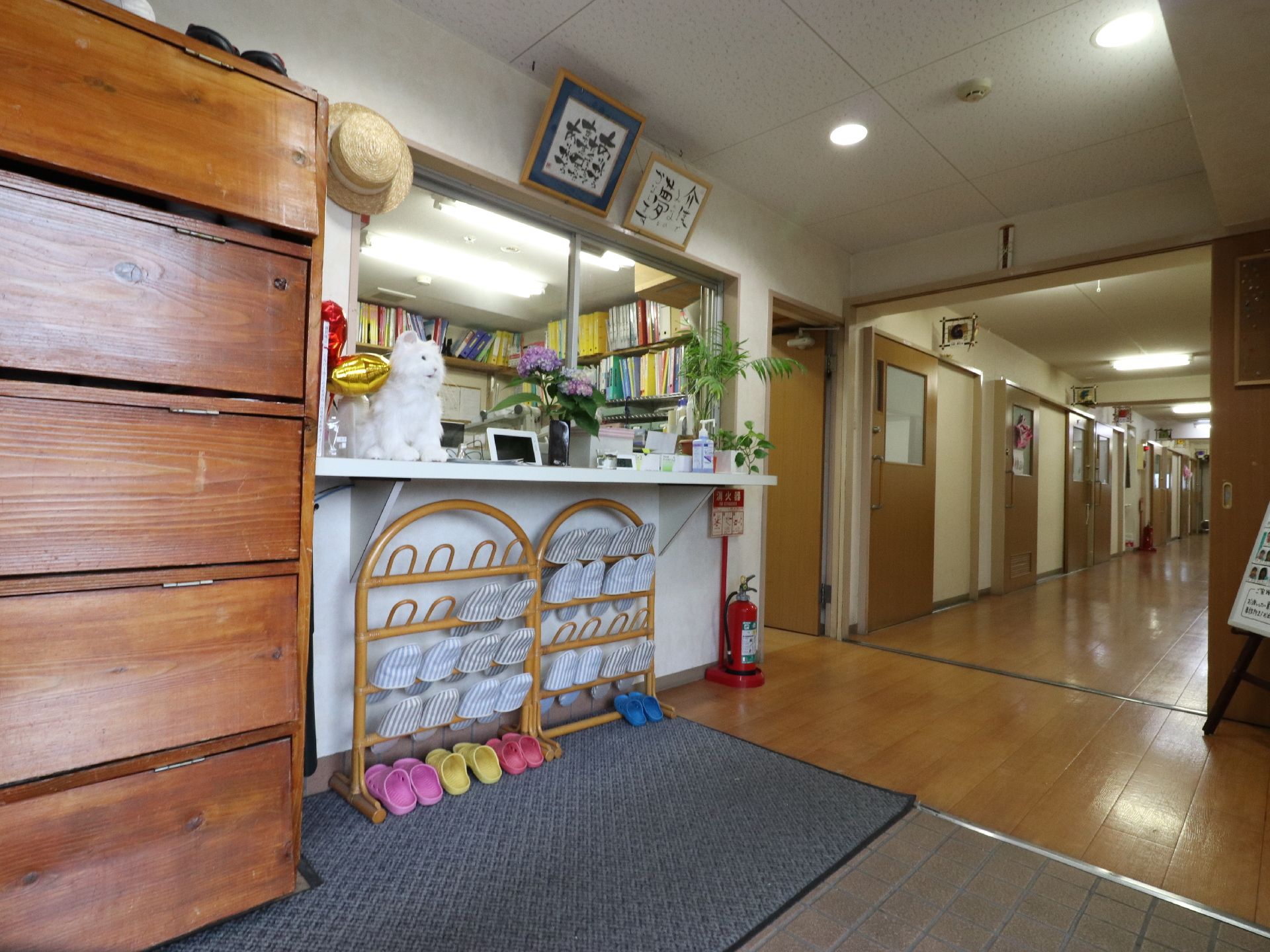 玄関入って上がり框のところに、木製の靴箱が置いてある。スリッパラックがマットの上に置いてあり、そこで靴を履き替える。