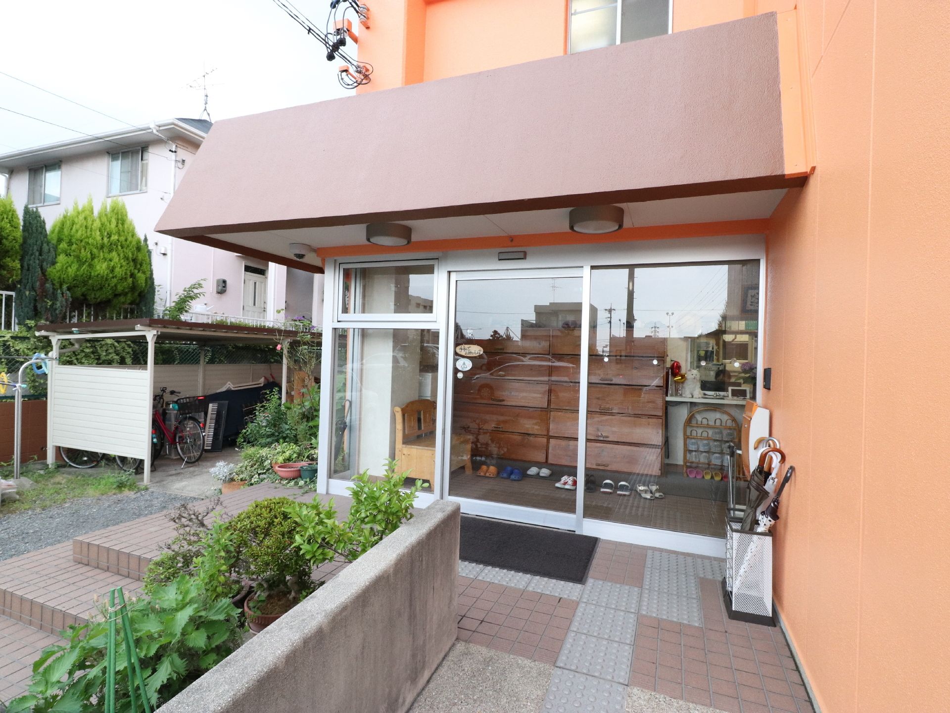 中に大きな木製の靴箱が見えているガラス張りのエントランス
