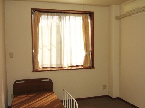 窓から光が差し込み、あたたかい雰囲気である。ベッドガードのついたシンプルなベッドが備え付けられている。