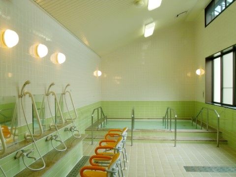 入居者様が自由に利用できる共同浴室である。洗い場にシャワーチェアを完備。浴槽には複数の手すりがつけられている。