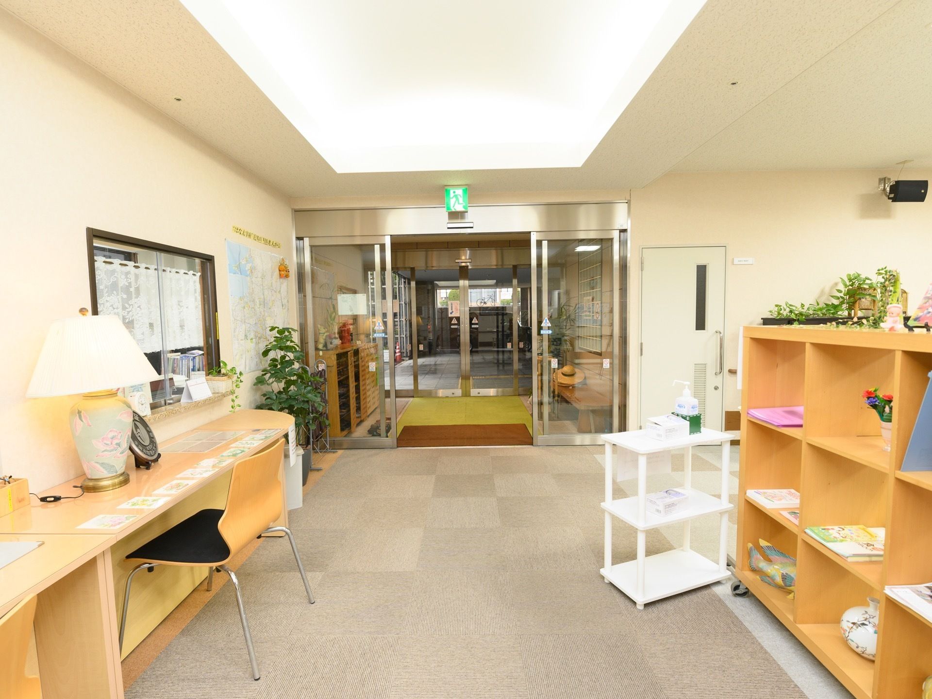 玄関内部は、大きな面積の間接照明でとても明るくなっている。受付窓口の前にはカウンターがあり、椅子が置かれている。