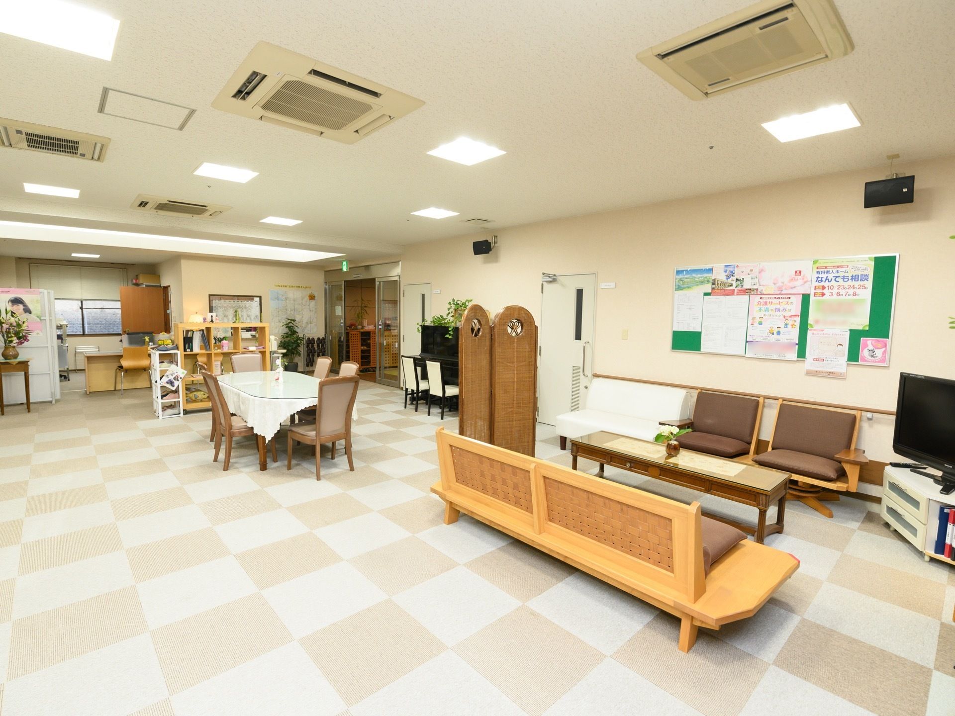 広い共有スペースがある。クロスがかかったテーブルや、横長のベンチ状の椅子、パーティションなどが置かれている。