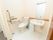 居室内のトイレである。大理石模様の床が使われ、洗面台がすぐそばに設置されている。室内とはカーテンで仕切られており、開けると開放感がある。