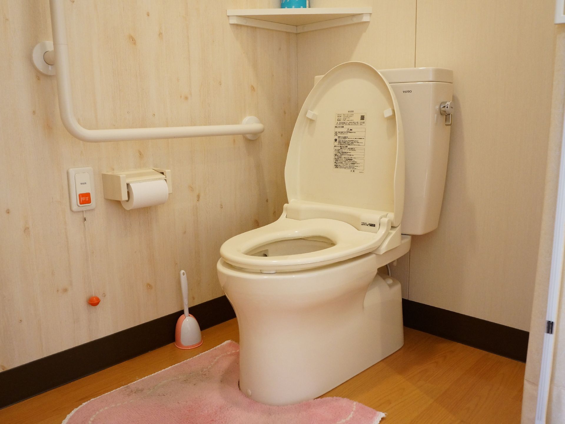 トイレには右手側にくの字の手すりがついている。呼び出しボタンには、床に近い位置まで伸びる紐が垂れている。