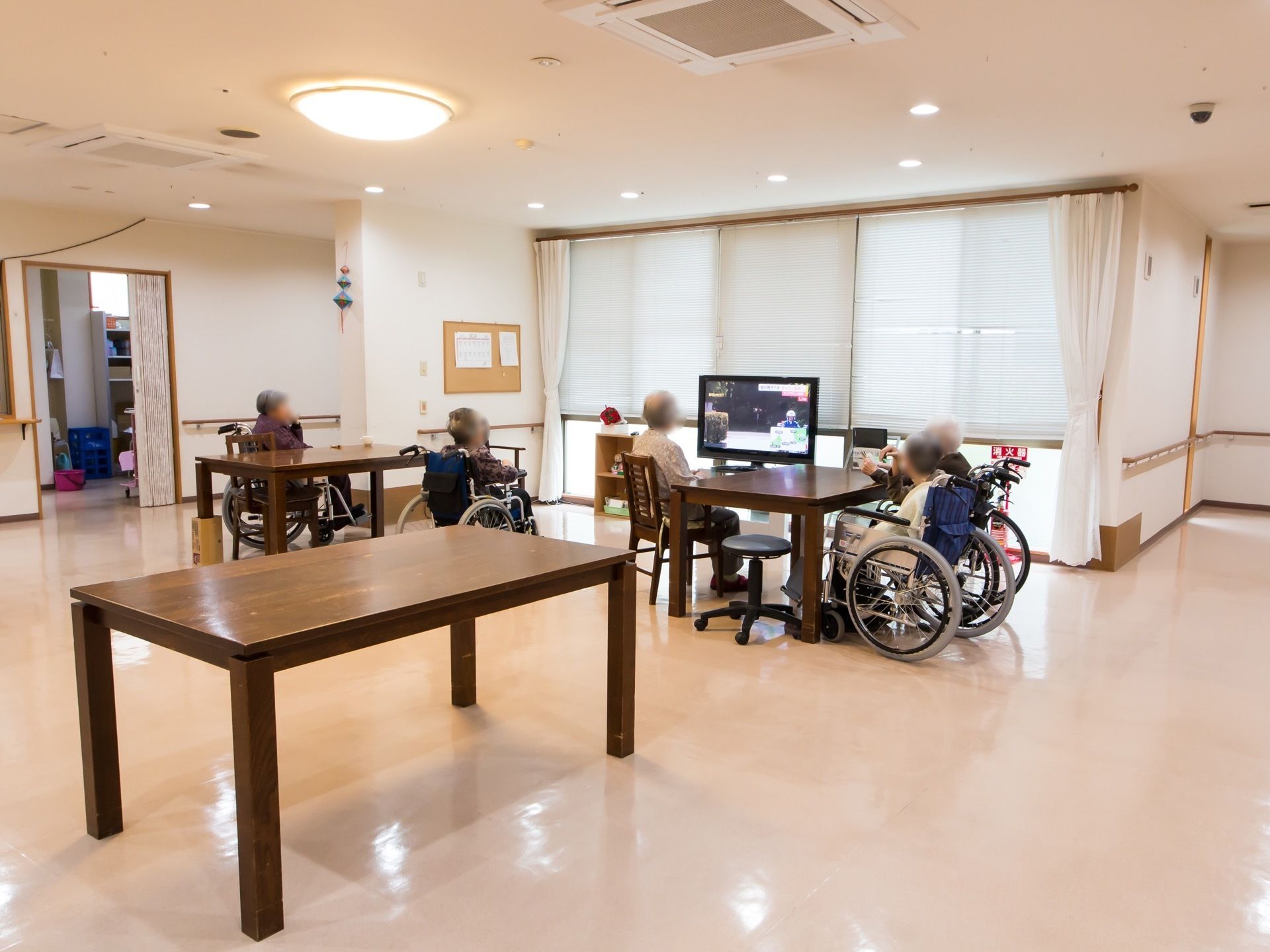 通路途中に設けられている開放的なリビングスペースで、入居者様各々が椅子に座り、テレビを一緒に楽しんでいる。
