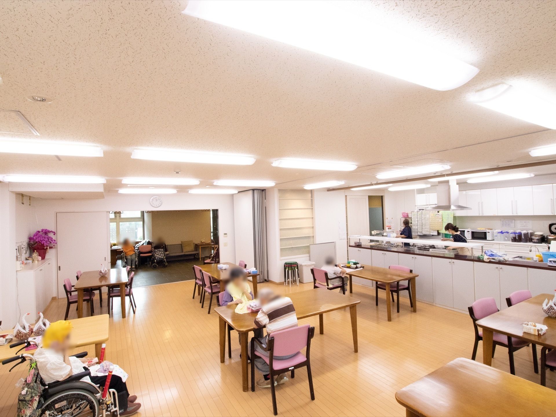 十分な間隔を確保してテーブルや椅子が配置されている。飲食スペースの隣に厨房がある。厨房は壁で仕切られておらず、スタッフや調理道具が見える。